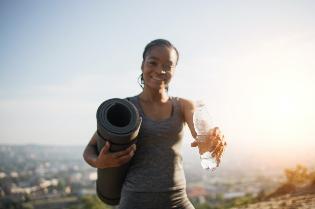 African woman in activewear holding bottle of water