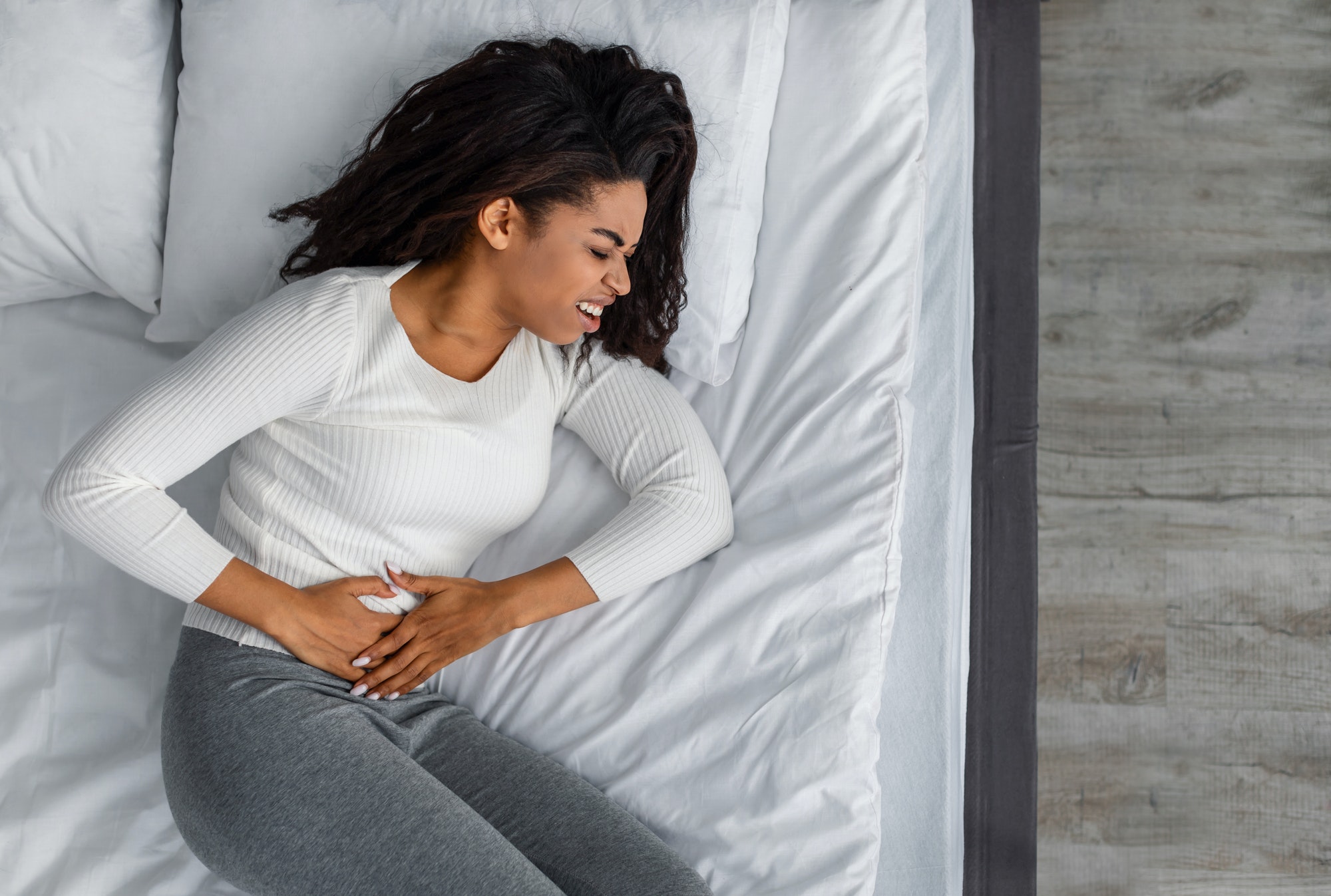 Black woman suffering from stomachache, touching her tummy