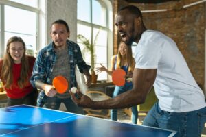 Young people playing table tennis in workplace, having fun
